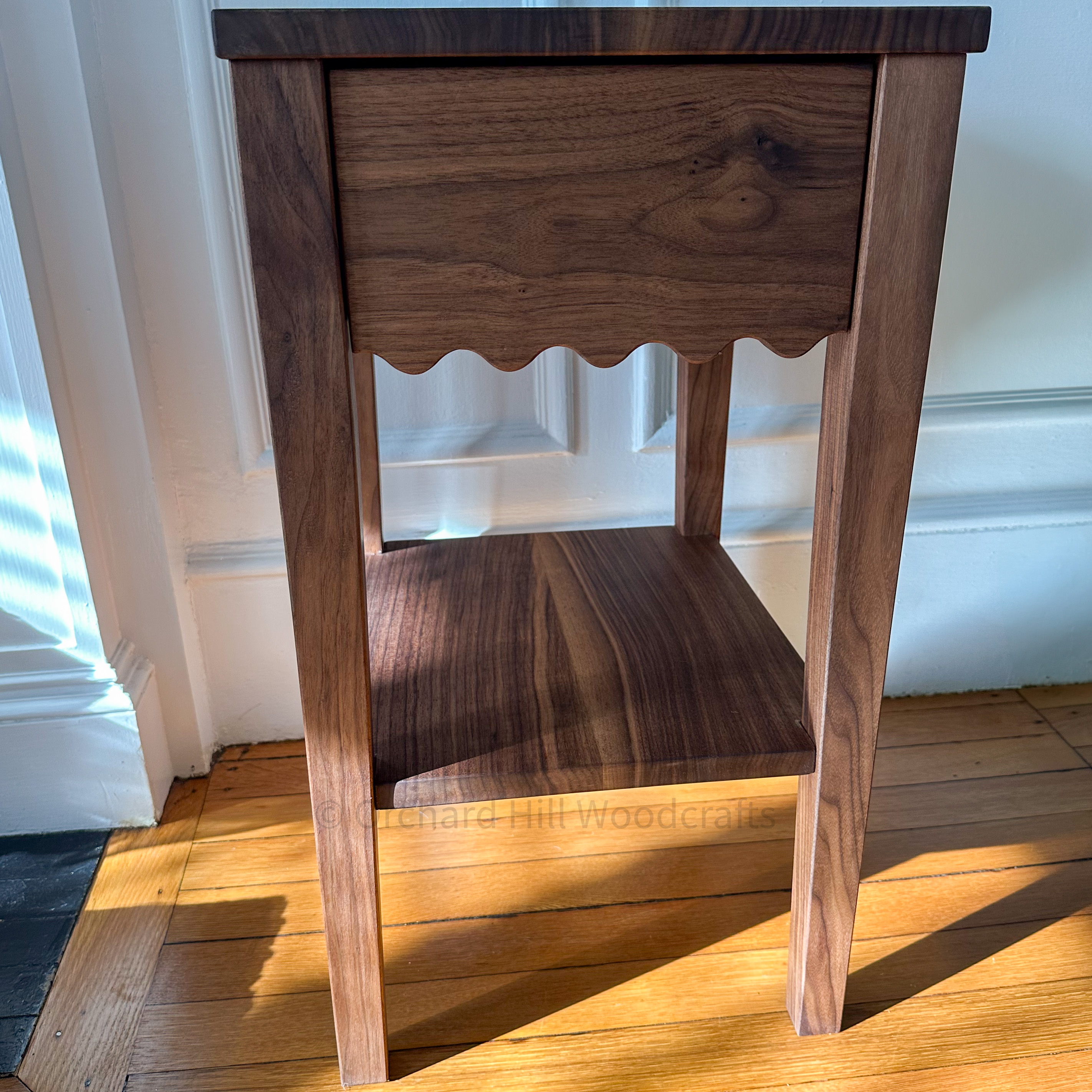 Walnut nightstand with scalloped apron and lower shelf